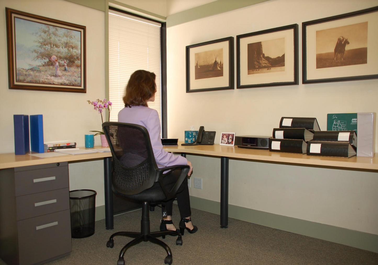 Under desk shelving before. Depicts a woman in an office with a cluttered desk.