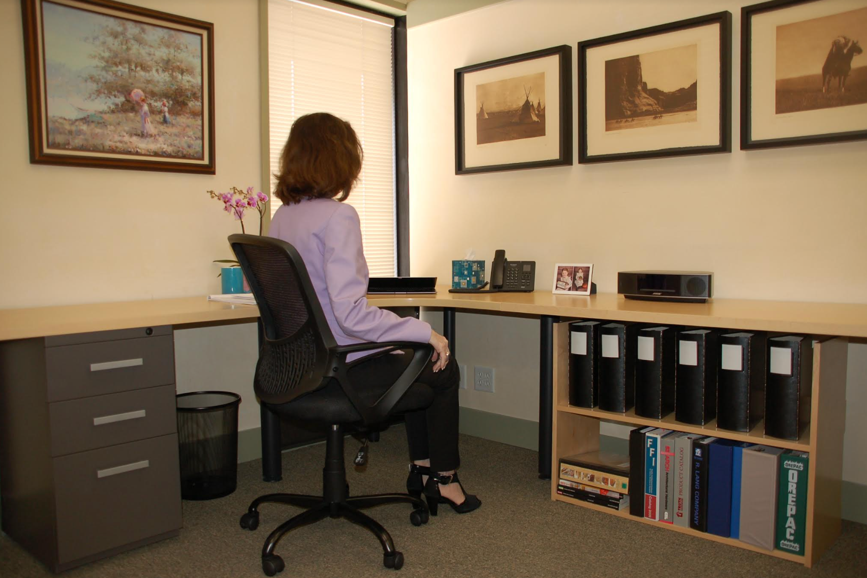 Under Desk Shelving after. Depicts a woman in an office, now organized.