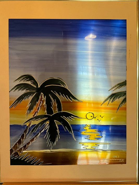 Framed artwork depicting a beach scene with palm trees and a sunset in the background.