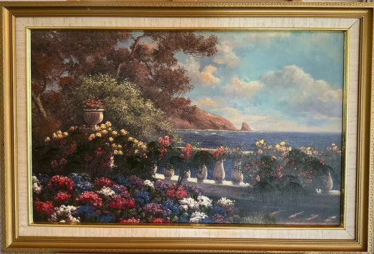 Framed artwork depicting an ocean view with floral elements and mountains in the background.